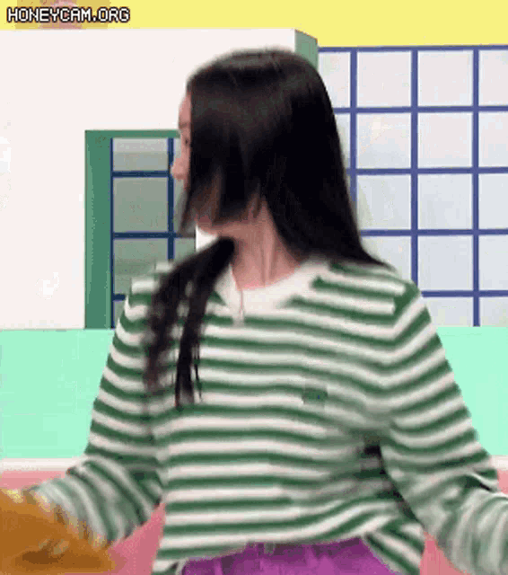 a woman is wearing a green and white striped sweater and purple skirt .