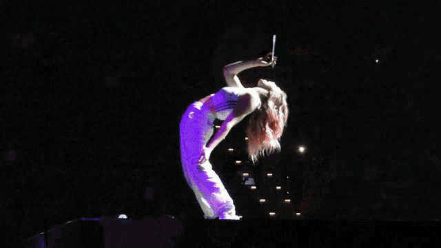 a woman performs on stage in front of a crowd including one wearing a shirt that says ' i love you '