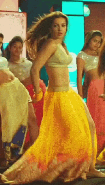 a woman in a crop top and yellow skirt is dancing