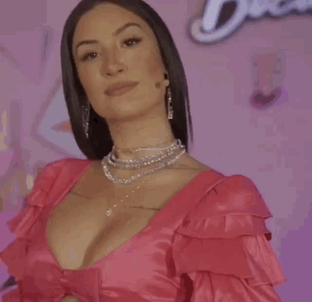 a woman with long black hair is smiling and wearing a pink shirt .