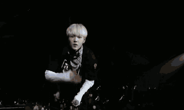 a young man with white hair and a bandana on his neck is making a funny face with his hands in the air .