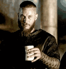 a man with a beard and mustache is holding a cup of coffee .