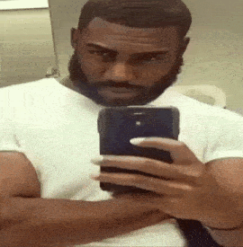 a man with a beard is taking a selfie with his phone in a bathroom .