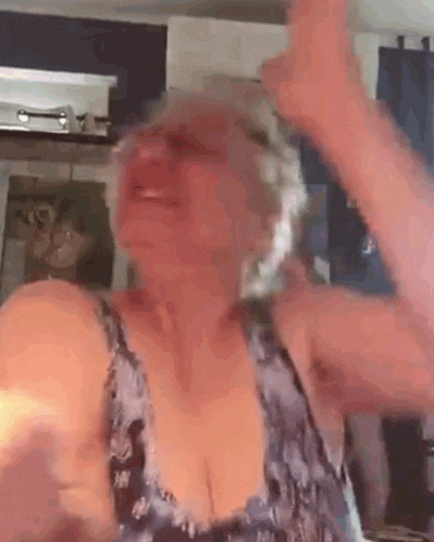 a woman in a blue tank top is dancing in a room .