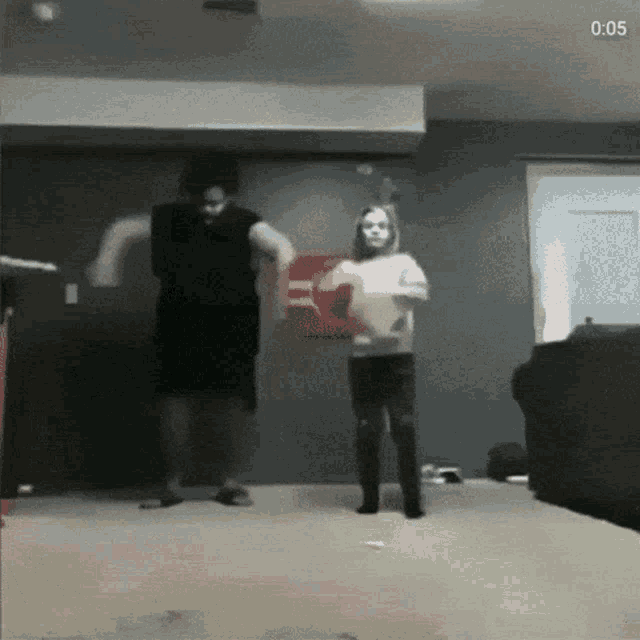 a man and a girl are dancing in a living room with the time of 0:05