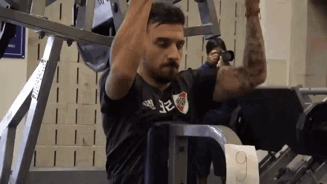 a man wearing a black shirt with the number 32 on it is doing exercises