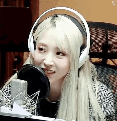 a woman wearing headphones is smiling in front of a microphone ..