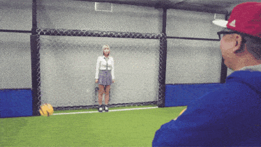 a woman in a plaid skirt stands in front of a soccer net