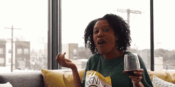 a woman is sitting on a couch holding a glass of wine .