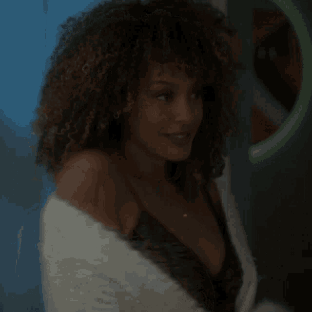 a woman with curly hair and a plunging neckline