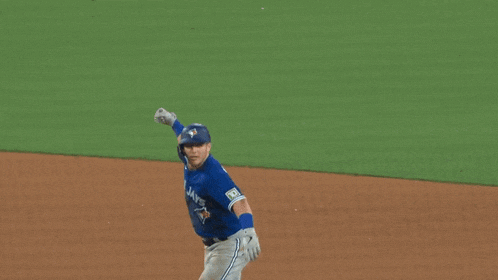 a baseball player wearing a blue jays jersey is running on the field .