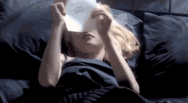 a woman laying in bed holding a piece of paper that says ' i love you '