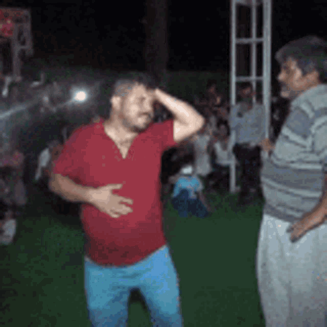 a man in a red shirt is dancing in front of a crowd .