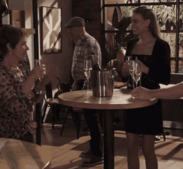 a group of people are standing around a table drinking champagne