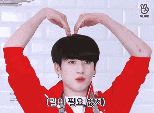 a young boy is making a heart shape with his hands .