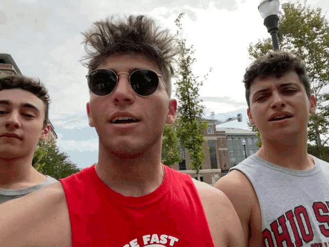 a man wearing sunglasses and a red tank top that says " fast "