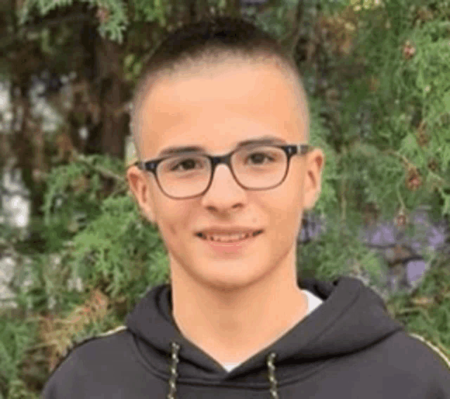 a young man wearing glasses and a black hoodie is smiling .