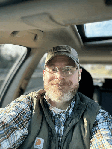 a man wearing glasses and a carhartt vest
