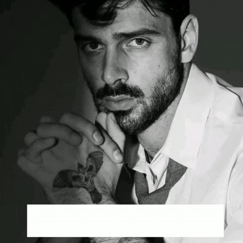 a black and white photo of a man with a tattoo on his arm