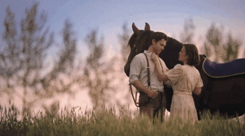a man and woman standing next to a horse