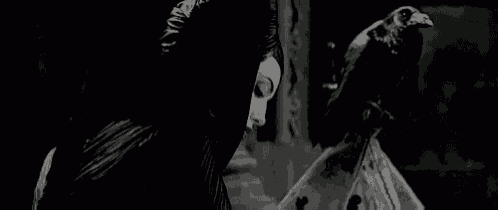 a black and white photo of a woman standing next to a statue of a crow .