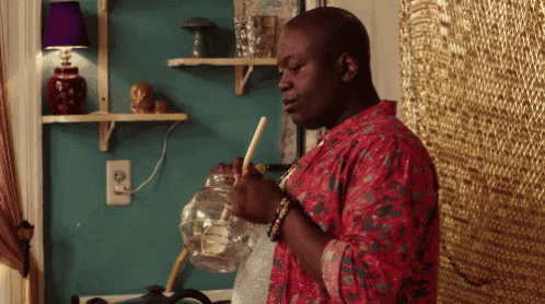 a man in a red shirt is smoking a hookah in a room