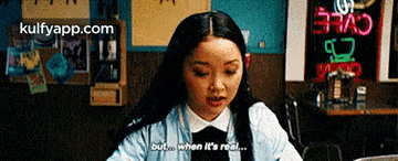 a woman is sitting at a table in a restaurant and saying but when it 's real