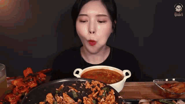 a woman is eating a meal with chopsticks and a spoon