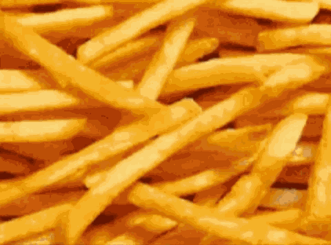 a pile of french fries on a table with a blurred background .