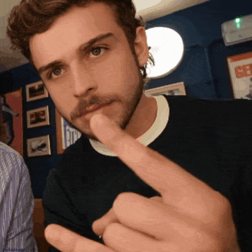 a man with a beard is making a gesture with his middle finger