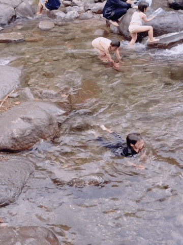 a group of people are playing in a river with rocks