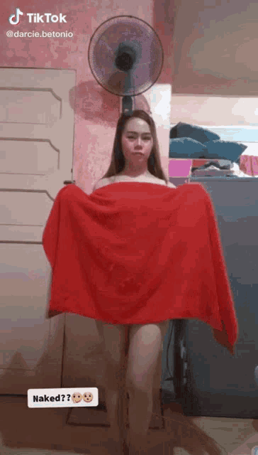 a woman is naked and holding a red towel in front of a fan that says tik tok