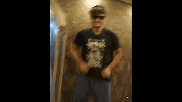 a blurry picture of a man wearing a hat and sunglasses dancing in a hallway .