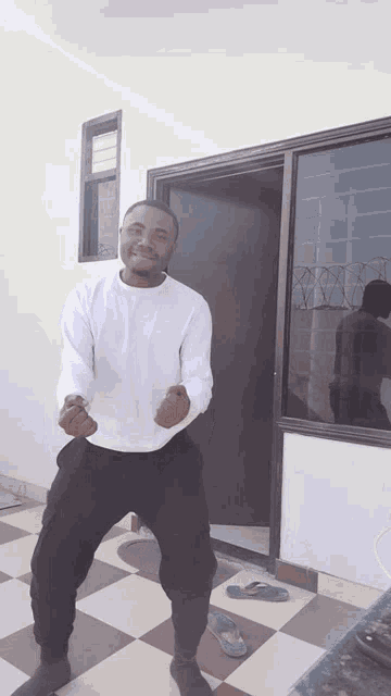 a man in a white shirt and black pants is dancing in front of a door