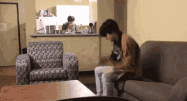 a man sits on a couch in a living room while a woman sits in a chair
