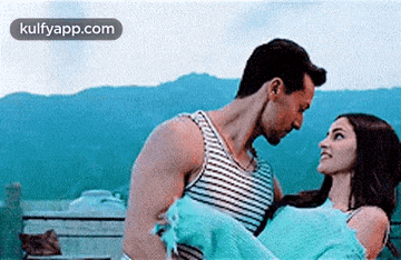 a man is carrying a woman in his arms while they look at each other .