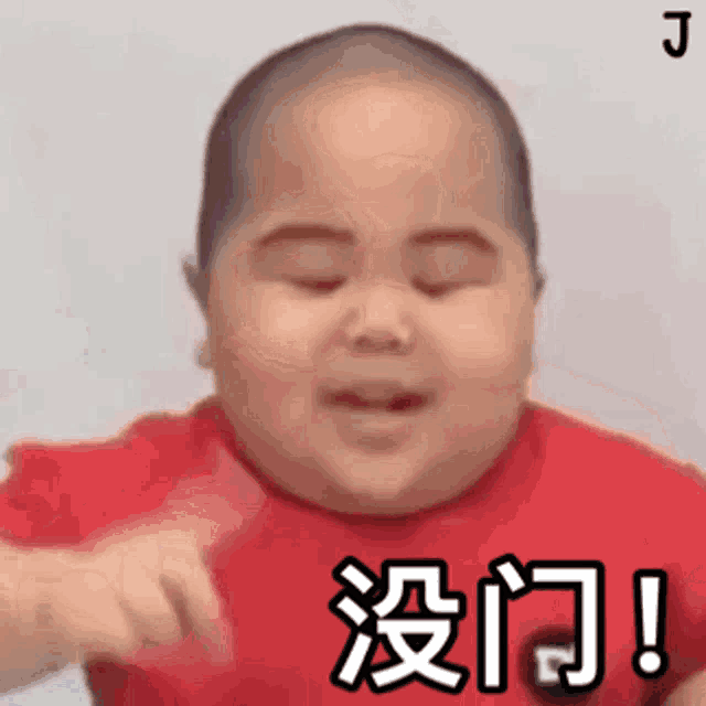 a baby in a red shirt is making a funny face with chinese writing on it .