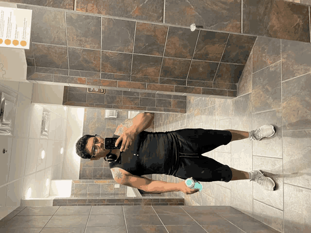 a man taking a picture of himself in a public bathroom