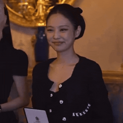 a woman in a black top is holding a tablet and smiling .