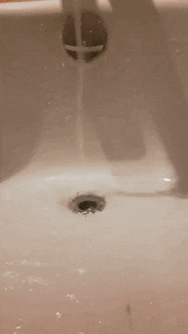 a close up of a sink with water coming out of the drain .