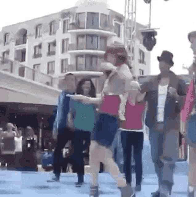 a woman is carrying a baby on her shoulders while a group of people are dancing on a stage .