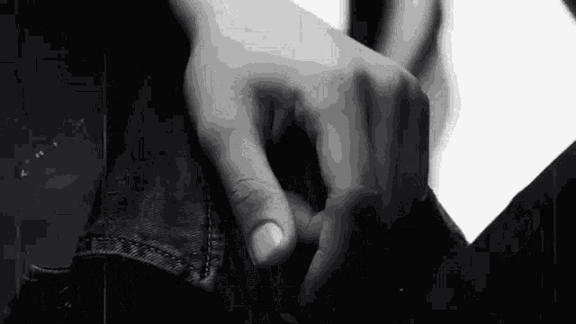 a black and white photo of a person 's hand reaching into a pocket of a jacket .