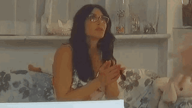 a woman wearing glasses is sitting on a couch and talking to another woman with the words il pisello below her