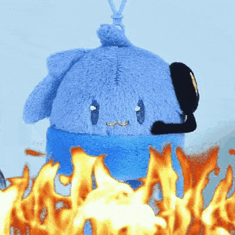 a blue stuffed animal with a headset is surrounded by fire