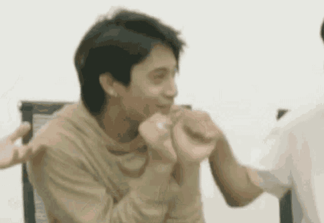 a man is holding another man 's hand and making a heart shape with his hands .