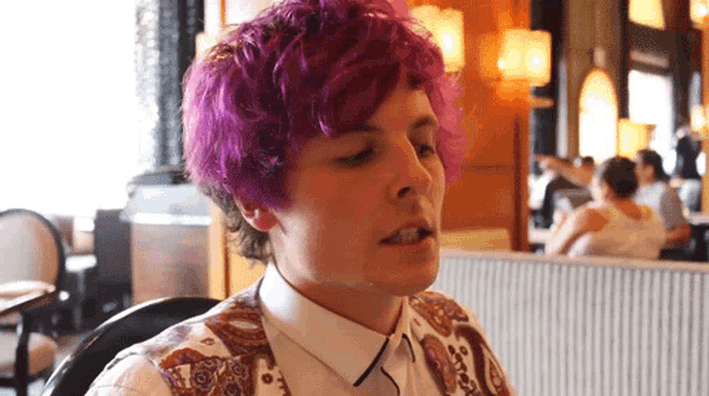 a woman with purple hair is sitting at a table