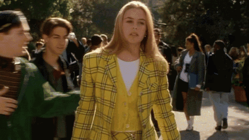 a woman wearing a yellow plaid jacket is walking down a street .