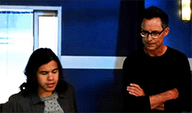 two men are standing next to each other in front of a blue wall .