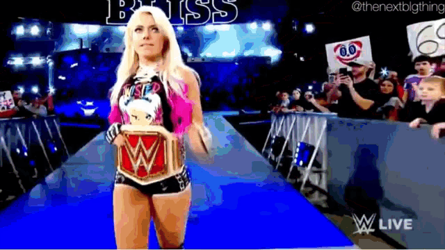 a female wrestler is walking down the aisle with a wwe championship belt