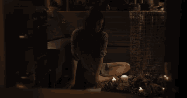 a woman sits on the floor in front of candles